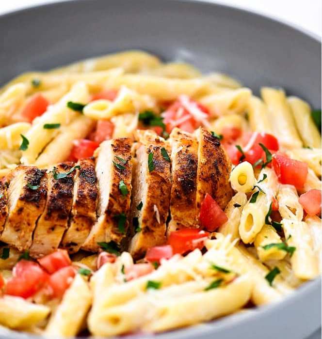 Chicken alfredo with diced tomatoes and penne noodles.